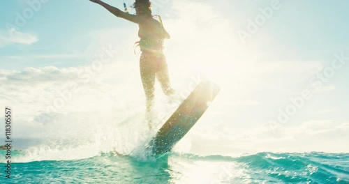 Beautiful young woman kiteboarding at sunset in slow motion, active lifestyle extreme sport