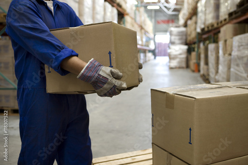 Worker carrying boxes in warehouse