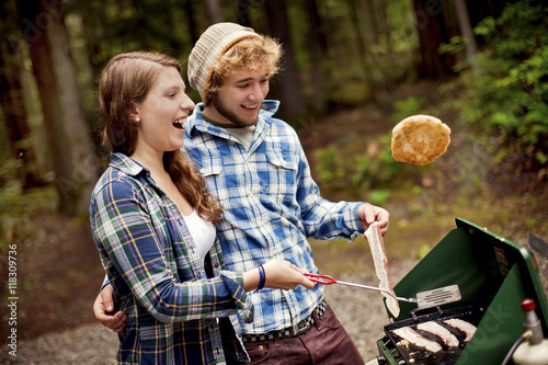 Couple cooking at camp stove in forest photo