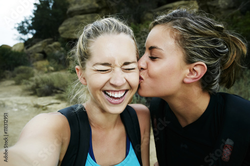 Woman kissing cheek of friend outdoors