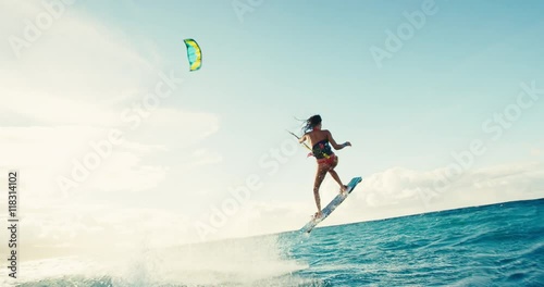 Beautiful young woman kiteboarding at sunset in slow motion, active lifestyle extreme sport