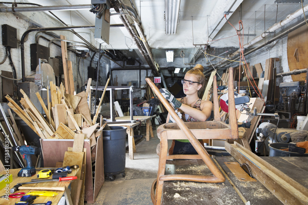 Caucasian woman working on wooden chair in workshop Caucasian woman working on wooden chair in workshop