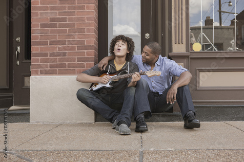 Father watching son playing electric guitar photo