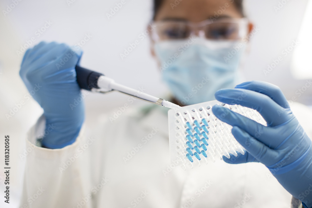 Mixed race scientist pipetting sample into test tube in laboratory ...