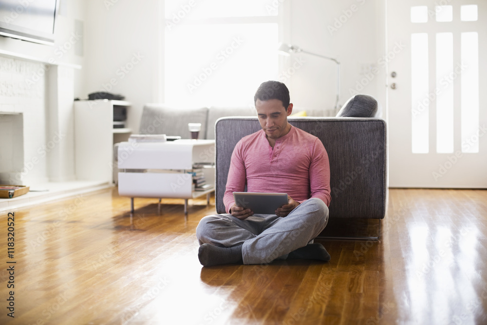 Mixed race man using digital tablet in living room Mixed race man using digital tablet in living room