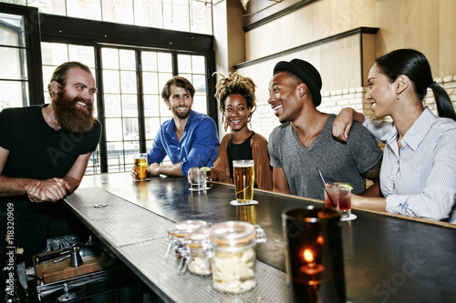 Smiling bartender and customers at bar photo