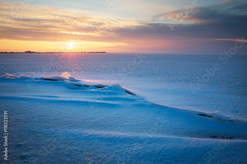 Beautiful winter landscape with frozen lake  crack and sunset sky