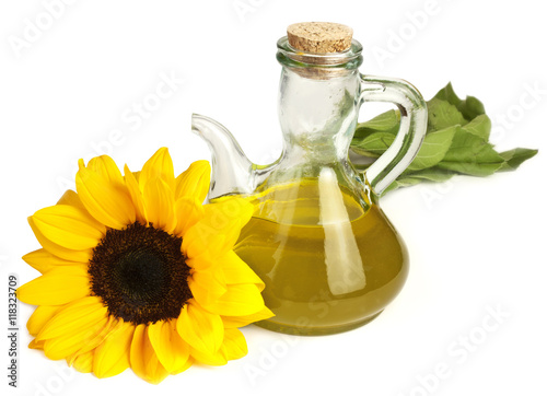 Vibrant yellow sunflower with pitcher of oil  isolated on white