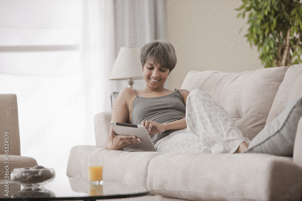 Mixed race woman on sofa using digital tablet Mixed race woman on sofa using digital tablet