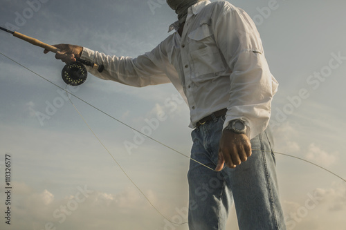 Close up of Caucasian man fishing under blue sky photo