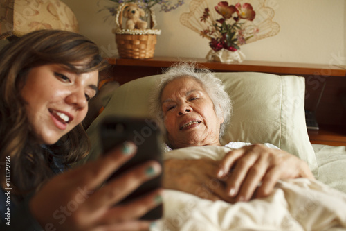 Grandmother and granddaughter taking selfie with cell phone in bed photo