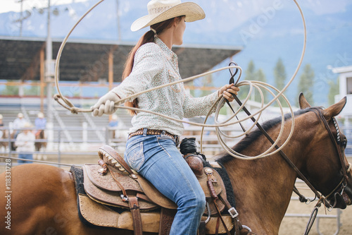 Caucasian cowgirl twirling lasso in rodeo photo