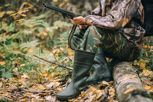 Male hunter in the autumn forest. A man holding a gun.