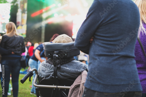 Disabled man in a special needs wheelchair watching a conecrt at a festival