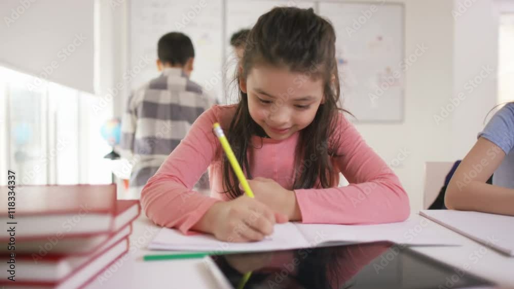 Portrait of happy little girl working at her desk in school classroom Portrait of happy little girl working at her desk in school classroom