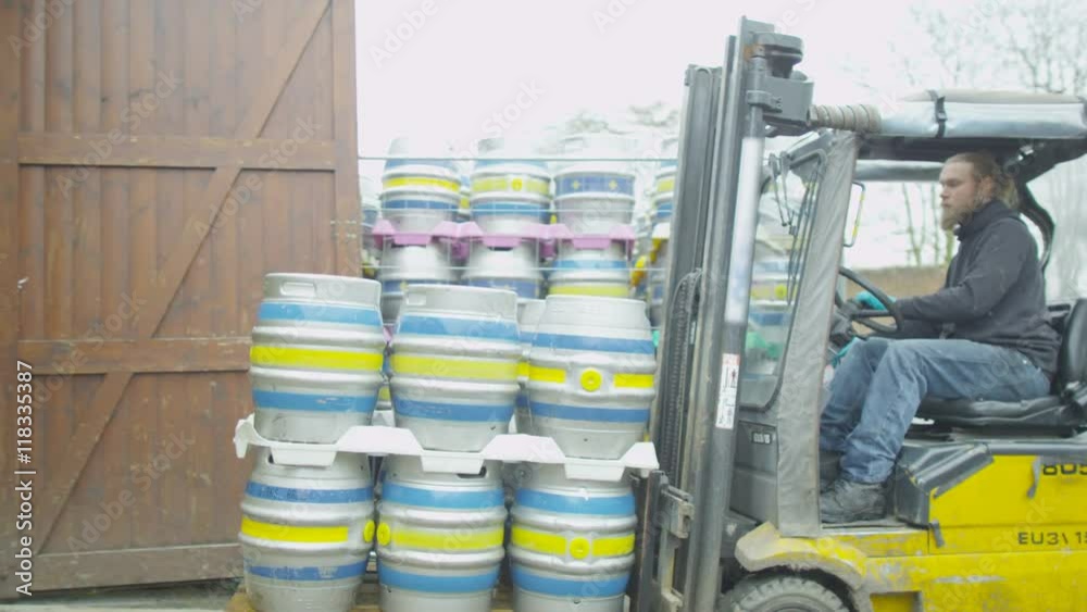 Brewery worker using a forklift truck to transport barrels of beer Brewery worker using a forklift truck to transport barrels of beer