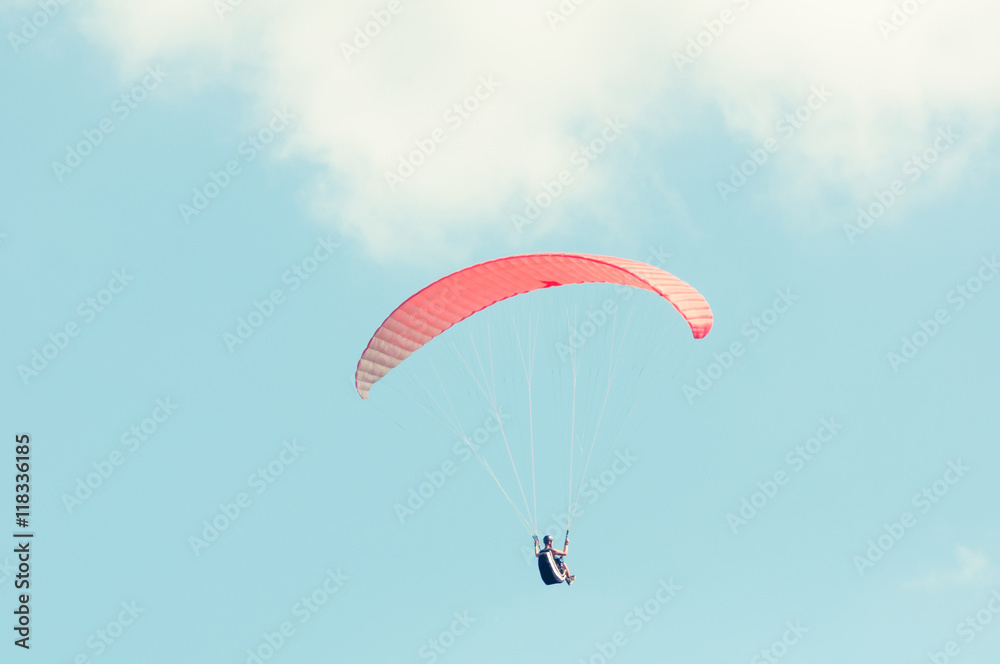 Paraglider flying up with red wing