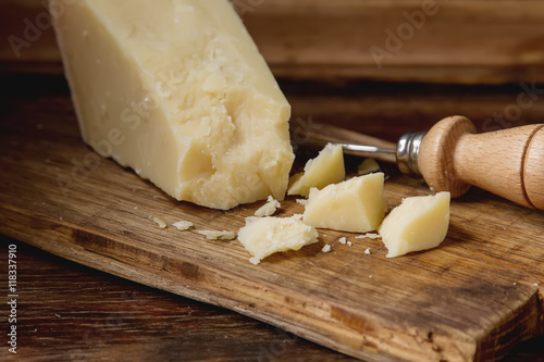 piece of Italian parmesan cheese with a knife. wood background,