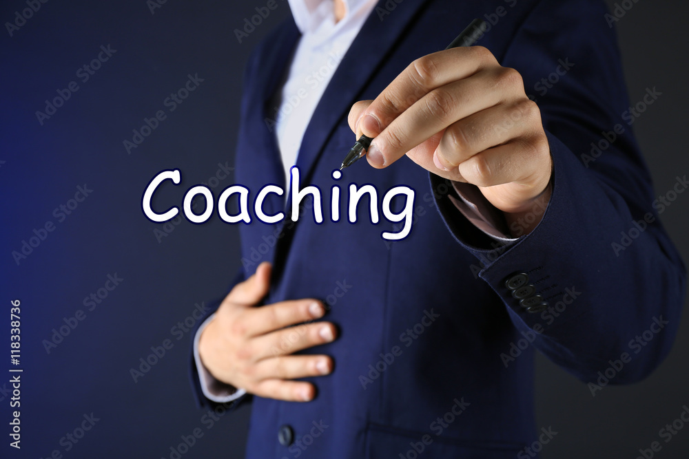 Leadership coaching concept. Businessman in suit with pen on dark background Leadership coaching concept. Businessman in suit with pen on dark background