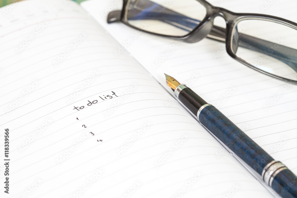 writing to do list on notebook page with pen on wood background writing to do list on notebook page with pen on wood background