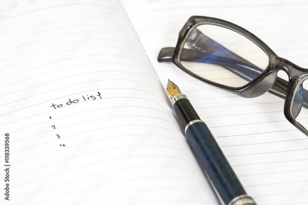 Fototapeta premium writing to do list on notebook page with pen on wood background