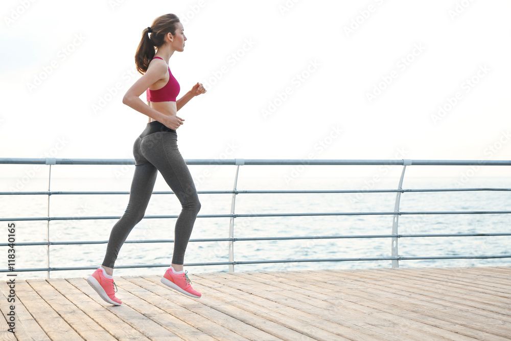 Fototapeta premium Young woman running on pier