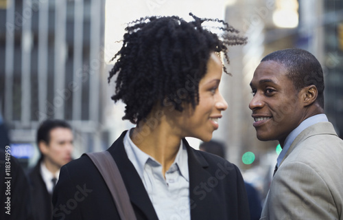 African American businesswoman smiling at businessman on street