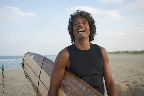 Mixed race man holding surfboard on beach