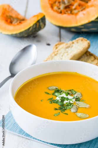 Pumpkin soup and ingredients on white wooden background


