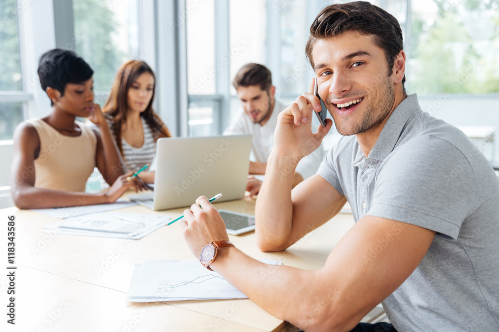 Businessman talking on mobile phone while working with business team Businessman talking on mobile phone while working with business team