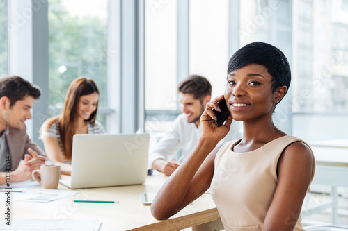 Businesswoman talking on cell phone while working with business team