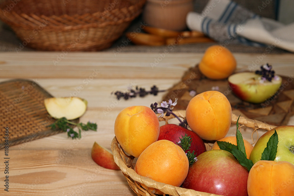 Apricots and apples in wattled basket on wooden table. Apricots and apples in wattled basket on wooden table.