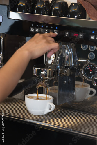 The worker prepares coffee with cream on the coffee machine