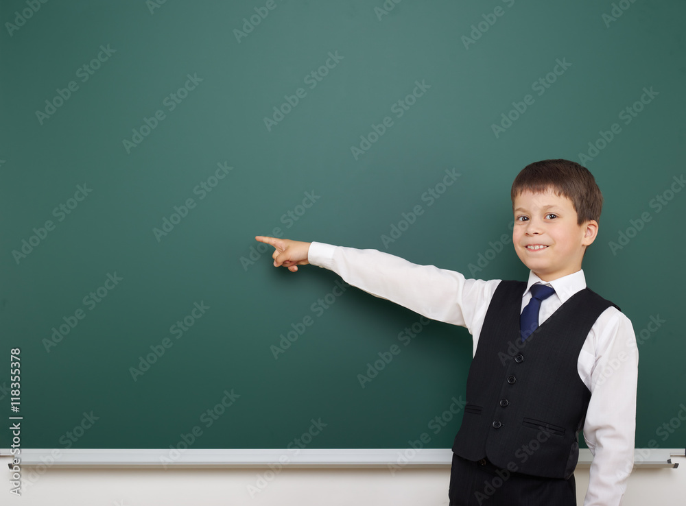 school student boy posing at the clean blackboard, show finger and point at, grimacing and emotions, dressed in a black suit, education concept, studio photo school student boy posing at the clean blackboard, show finger and point at, grimacing and emotions, dressed in a black suit, education concept, studio photo