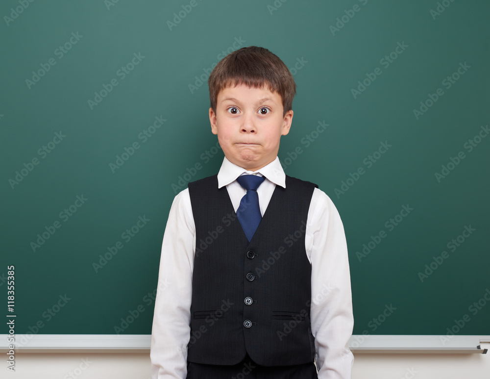 school student boy posing and think at the clean blackboard, grimacing and emotions, dressed in a black suit, education concept, studio photo school student boy posing and think at the clean blackboard, grimacing and emotions, dressed in a black suit, education concept, studio photo