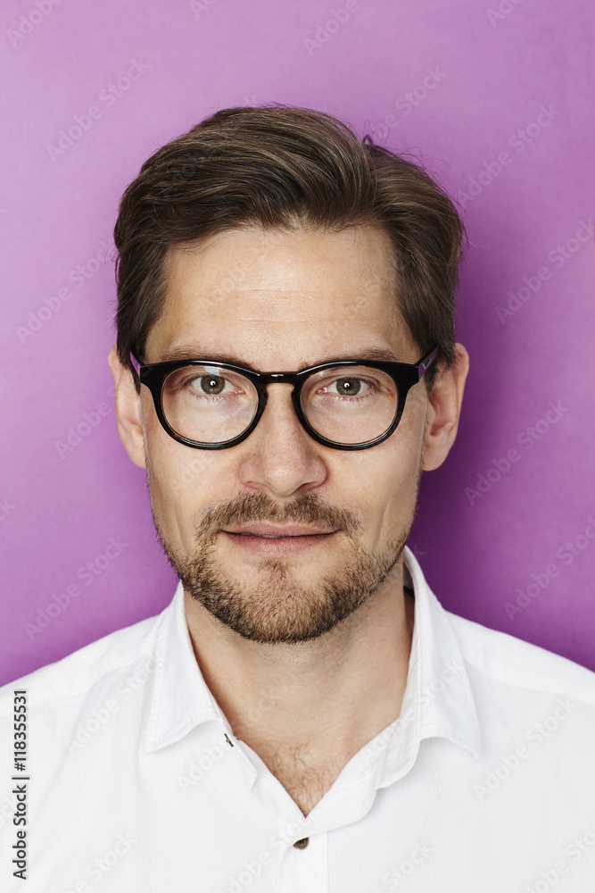 Handsome man in spectacles, portrait against purple