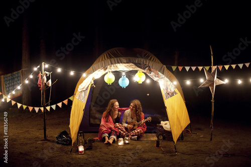 Girls relaxing in camping tent at night photo