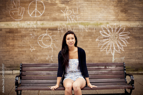 Woman sitting on urban bench near graffiti wall photo