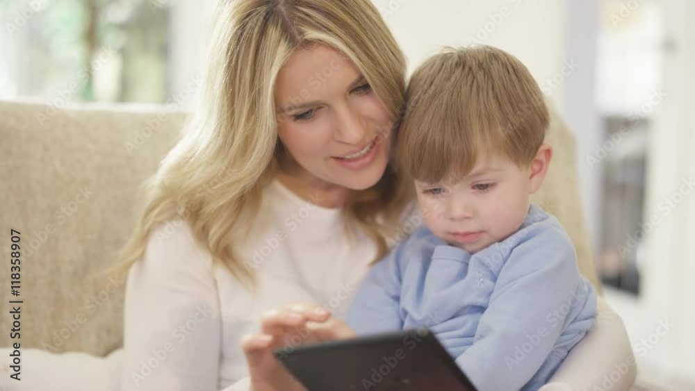 Mother & cute young son looking at computer tablet together at home Mother & cute young son looking at computer tablet together at home
