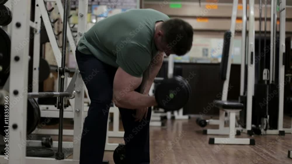 Bodibilder shakes her biceps with dumbbells in the gym Bodibilder shakes her biceps with dumbbells in the gym