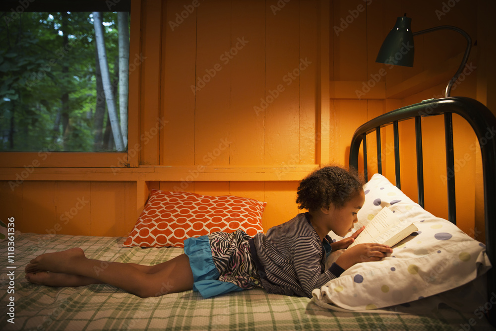 Mixed race girl reading on bed Mixed race girl reading on bed