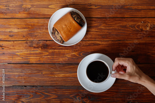 Woman's hand with cup of coffee and croissant, top view