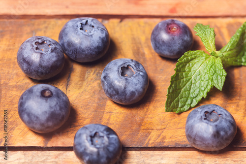 Gruppe Heidelbeeren mit Minzblatt auf Holzbrett