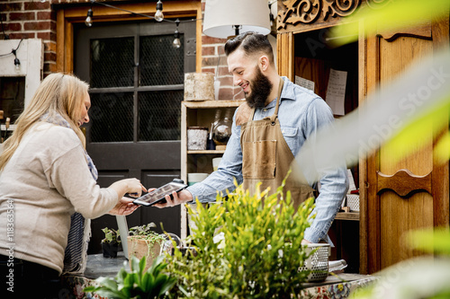 Employee helping customer with digital tablet in store