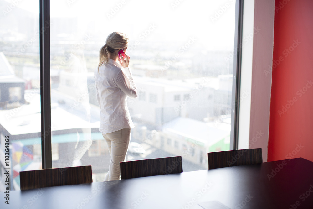 Caucasian businesswoman talking on cell phone in conference room Caucasian businesswoman talking on cell phone in conference room