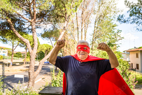 senior posing as superhero with red cloack and mask photo
