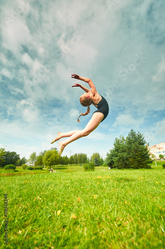 Young beautiful preteen girl doing gymnastics outdoors