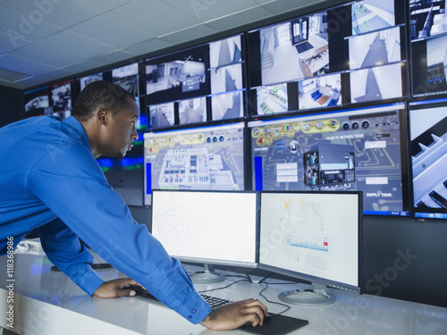 Black security officer watching surveillance cameras photo