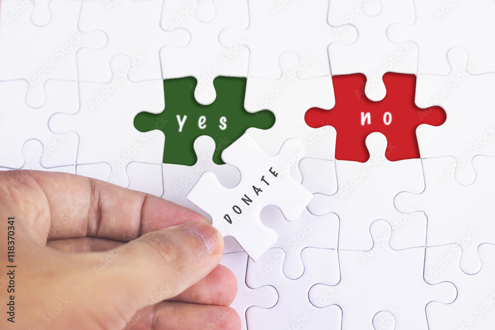 Business Concept - Female hand and missing puzzle with DONATE, YES NO WORD Business Concept - Female hand and missing puzzle with DONATE, YES NO WORD