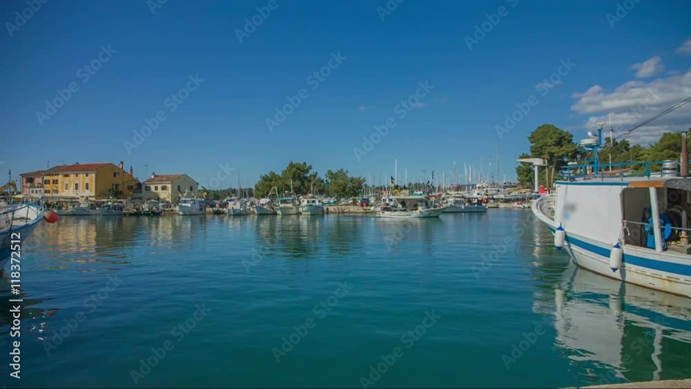 It is early morning time and the ships and boats are parked in the harbour. The sea is peaceful and the sun is shining. Wide-angle shot.

